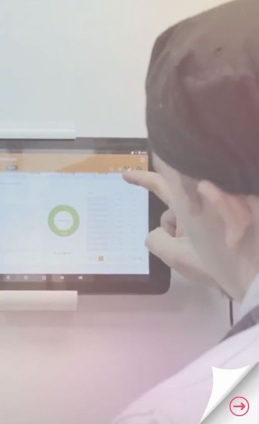 A chef scrolls through the Navitas Safety Food Safety Dashboard on a tablet attached to the wall of the kitchen