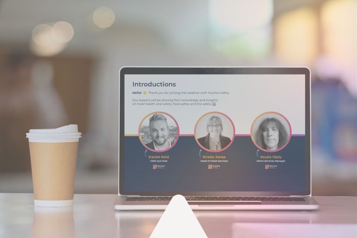 A laptop with a Navitas Safety webinar on the screen is sat on a table with a coffee to the left